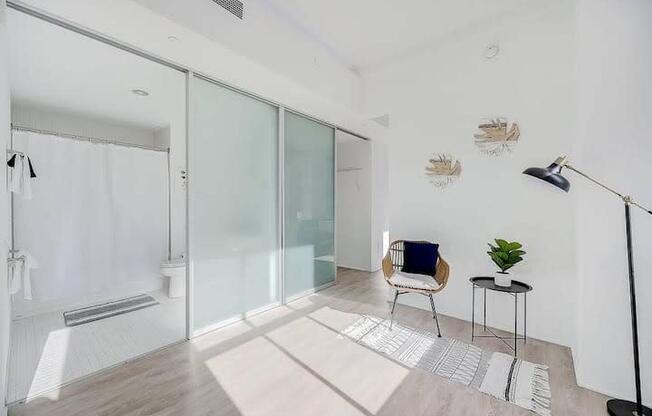 a white bathroom with a glass shower and a chair