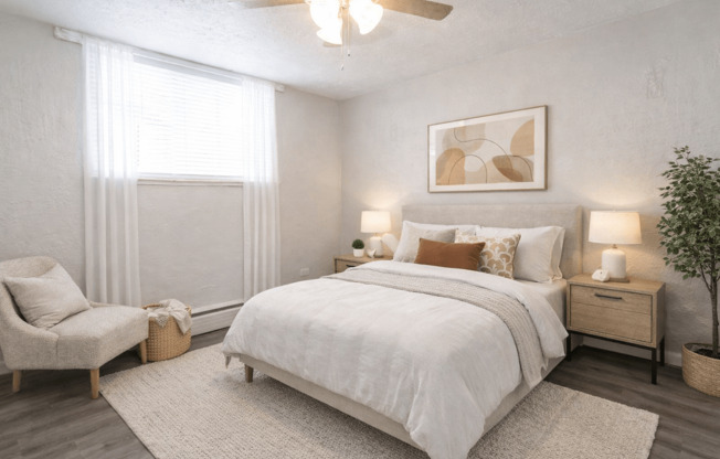 A bedroom with a large bed, a chair, and a ceiling fan.