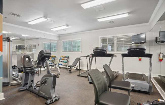 a gym with treadmills and other exercise equipment and windows