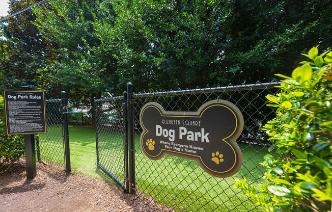 a sign for dog park in front of a fence