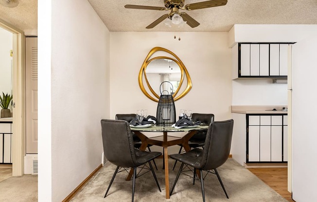 Aurora, CO Apartments – Ivy Crossing – A dining room with a round mirror and a table with chairs.