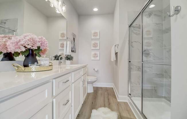 A white bathroom with a marble shower and a white vanity.
