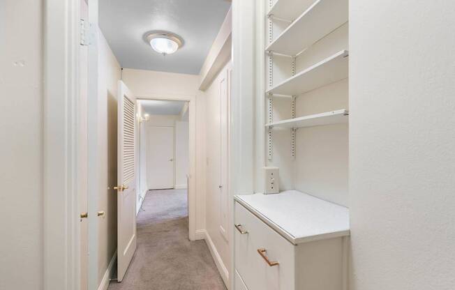 a walk in closet with white cabinets and a white counter