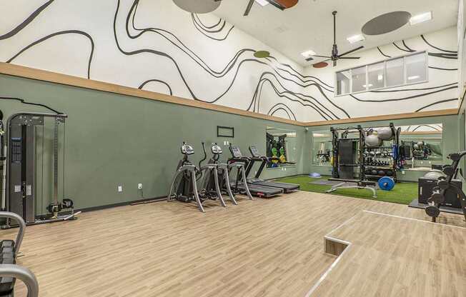 A gym with a green wall and wooden floor.