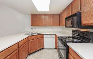 A kitchen with wooden cabinets and a black microwave above the stove.