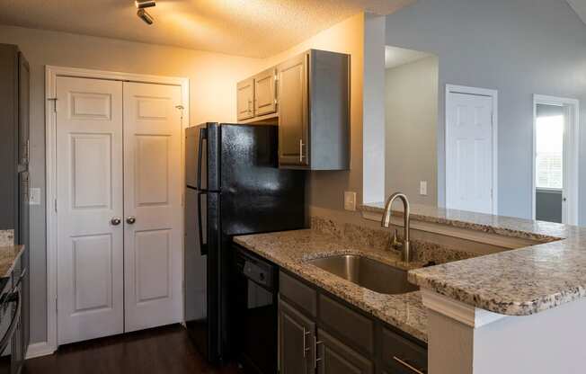 a kitchen with granite countertops and a black refrigerator