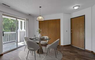A dining room with a table set for two and a view of a deck outside.