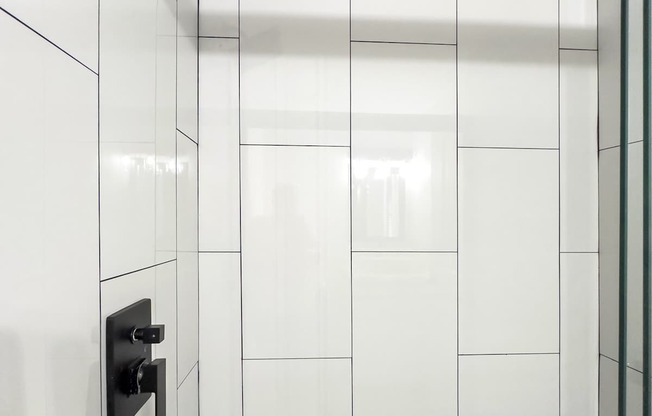 Retreat at Indian Lake apartments in Hendersonville, TN white tiled shower with a black shower head.