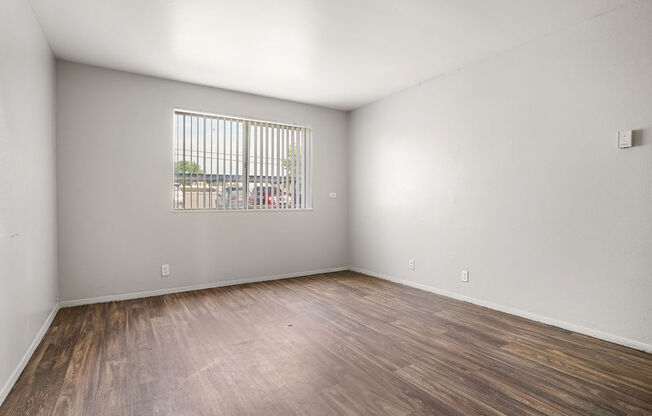 an empty living room with wood flooring and a window