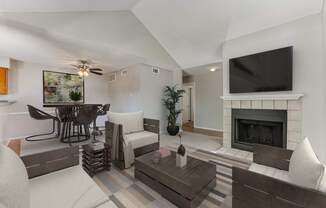A living room with a fireplace and a television mounted above it.