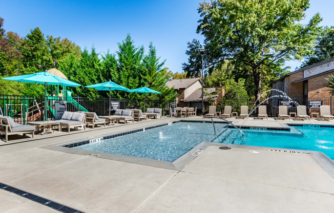 our resort style swimming pool is surrounded by lounge chairs and umbrellas