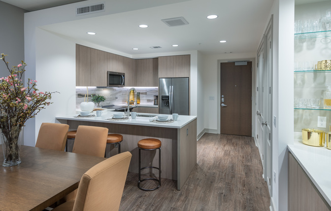 Open-concept kitchen with dark wood-style floors, a large peninsula, stainless steel appliances, and ash-blond wood cabinets.