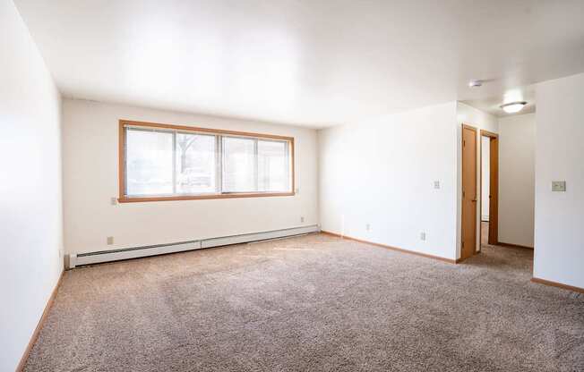 A room with a window and carpeted floor. Fargo, ND Birchwood 2 Apartments