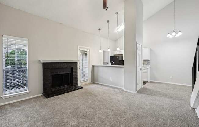 A living room with a fireplace and a kitchen area in the background.