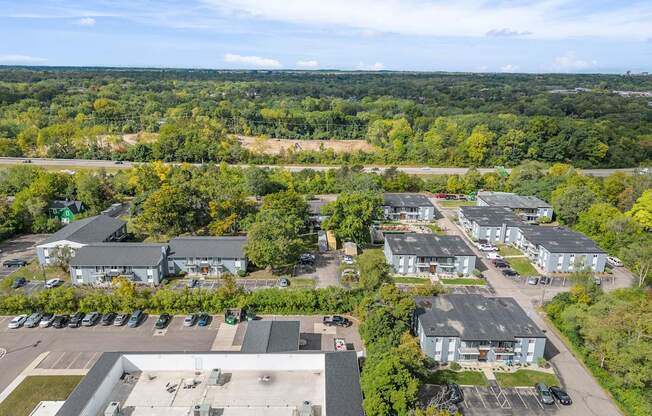 A bird's eye view of a parking lot and buildings surrounded by trees.