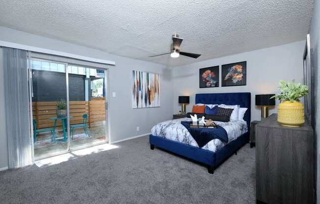Apartments for Rent Arlington TX- Stadium 700 Apartments Modern Bedroom With Natural Light, Cozy Carpeting, Ceiling Fan, and Patio Access
