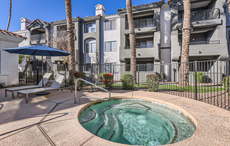 A pool surrounded by a black fence with a building in the background.