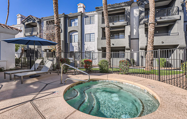 A pool surrounded by a black fence with a building in the background.
