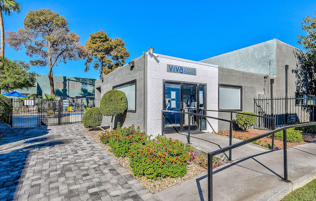 A building with the word "VIVA" on it is surrounded by a gate and has a walkway leading to the entrance.