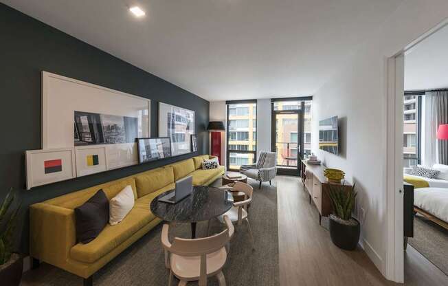 a living room with a yellow couch and a black wall and a balcony