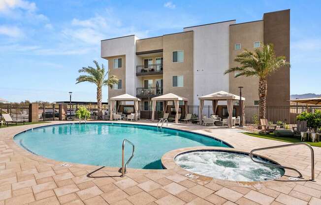 A large swimming pool with a hot tub in front of a building.