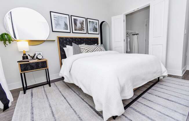 a bedroom with a white bedspread and black and white pictures on the wall
