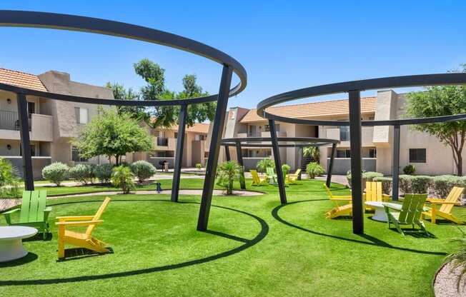 an outdoor lounge area with yellow lounge chairs and green grass with apartment buildings in the background