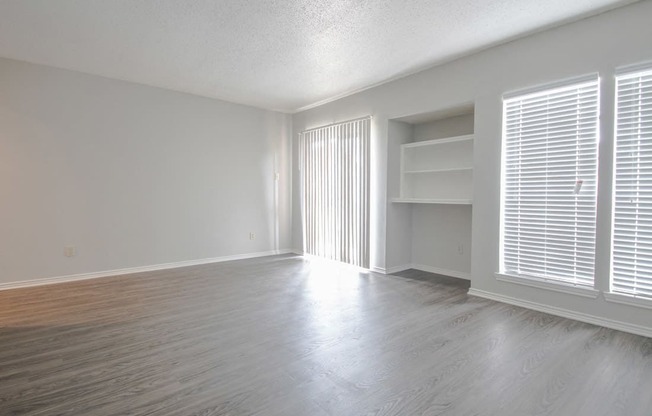 an empty living room with wood flooring and a large window at The Broadwater at Salado Creek, San Antonio, TX, 78216