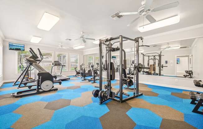 a gym with weights and cardio machines and ceiling fans