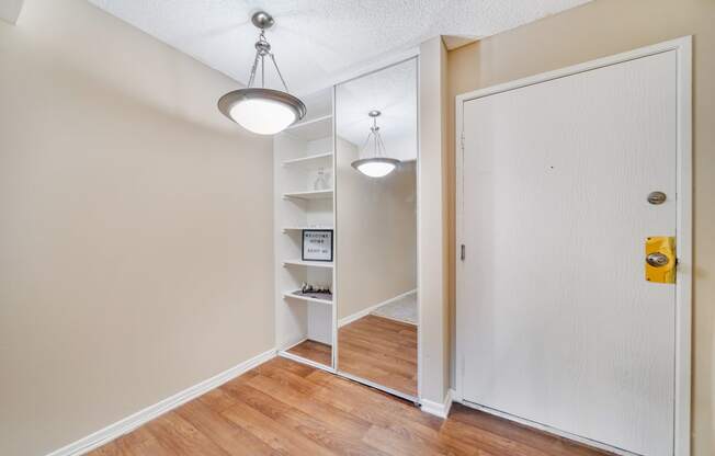 a bedroom with a closet and a door to a hallway with a mirror and lights