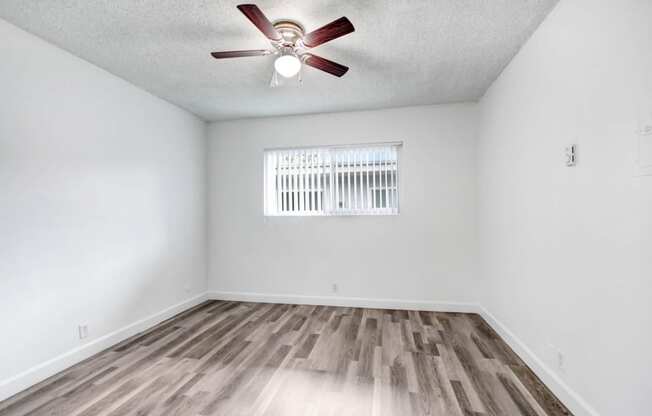 an empty living room with a ceiling fan and a window