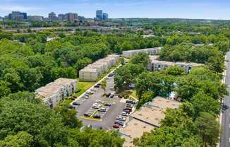 an aerial view of an apartment complex with trees and a city in the background