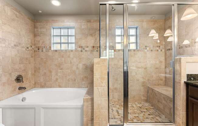 A bathroom with a white tub and a walk-in shower. at Bridge at Heritage Woods, Austin, 78753