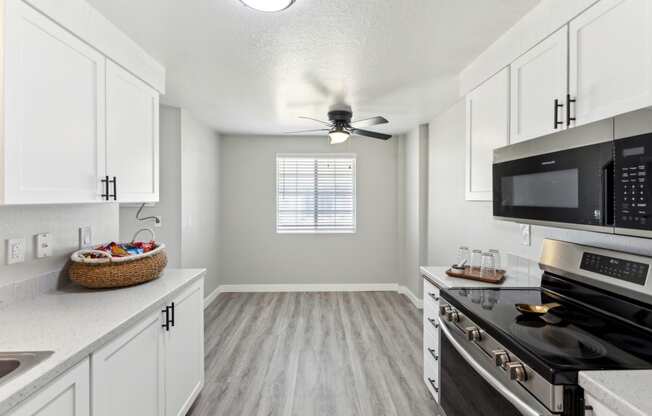 an empty kitchen with white cabinets and black appliances and a ceiling fan