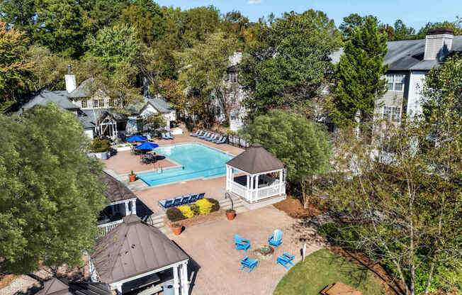 A pool surrounded by trees and a gazebo.