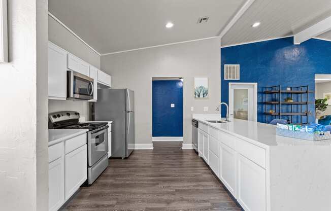a kitchen with white cabinets and a blue wall