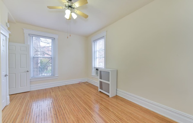 vacant bedroom with hardwood floors, large windows and ceiling fan at dupont apartments in washington dc