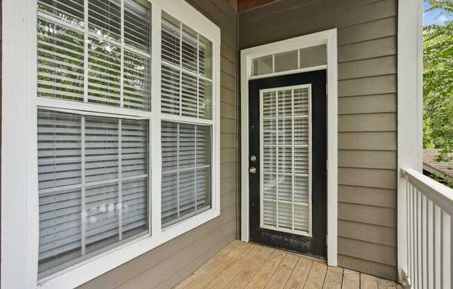 A black door with white blinds on the side of a house.