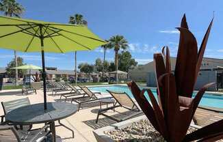 A pool area with a table and chairs and umbrellas.