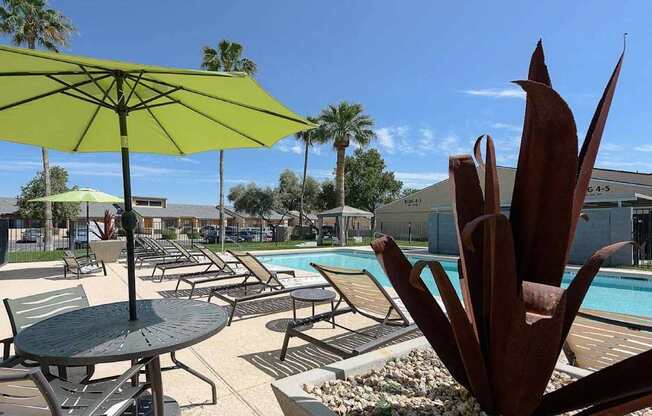 A pool area with a table and chairs and umbrellas.
