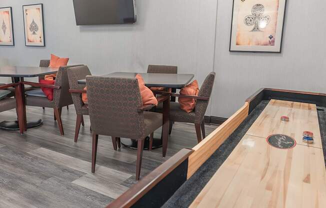 A room with a shuffleboard table and chairs.