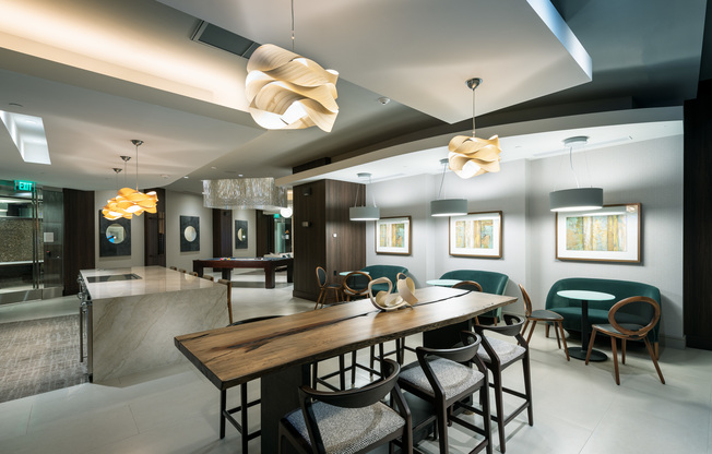 Resident catering kitchen with barstools at a large marble island, cafe-style seating along the wall, and a 6-person wood dining table.