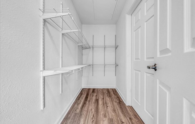 the closet in a bedroom with white walls and wood flooring