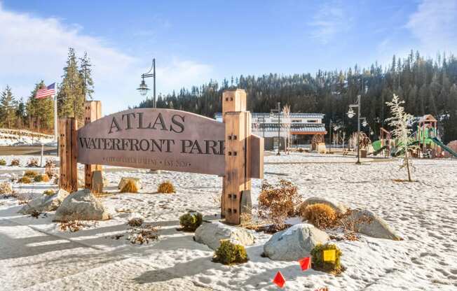 a sign that reads atlas westfront park with a playground in the background