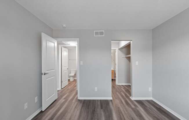 the living room of an apartment with white walls and wood flooring