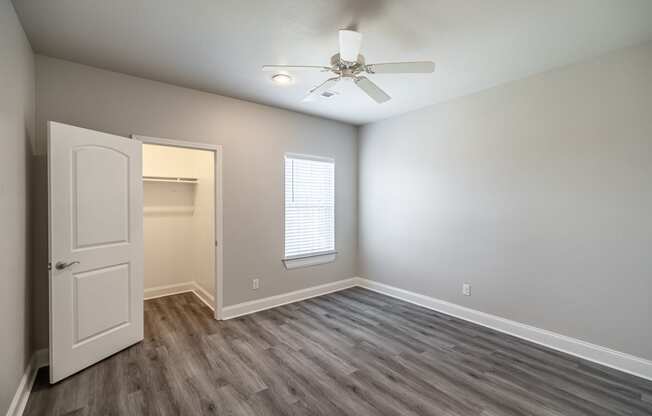 an empty room with a white door and a ceiling fan