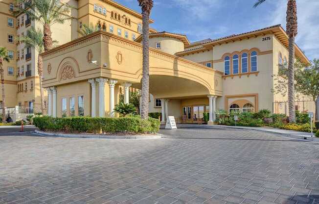 A large, beige building with palm trees in front.