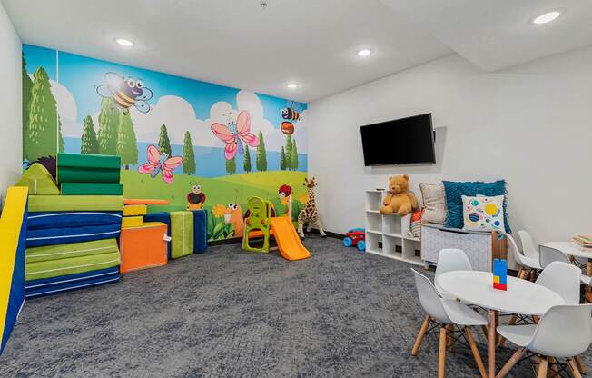a play room with chairs and toys and a wall mural