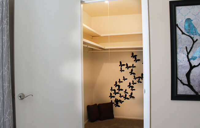 a walk in closet with a large white shelf and a flock of birds on the wall