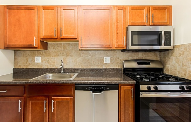 a kitchen with wooden cabinets and a sink and a stove at penn view apartments in washington dc